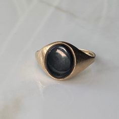 A vintage 9 carat gold Onyx signet ring.  CONDITION: Wear consistent with age and use. Damage to back of the stone. Please see photos for more detail. ASSAYED IN BIRMINGHAM, HALLMARKED 9 CARAT GOLD  RING SIZE: UK: W | US: 11 BAND WIDTH (SMALLEST POINT): 1.5mm FACE SIZE: 12mm x 10mm WEIGHT: 2.3 grams (SZ) Vintage Signet Ring For Anniversary, Vintage Oval Cabochon Signet Ring For Formal Events, Vintage Signet Ring With Cabochon For Anniversary, Antique Gemstone Signet Ring For Anniversary, Vintage Engraved Round Sapphire Ring, Vintage Engraved Ring With Cabochon For Anniversary, Domed Gemstone Signet Ring For Anniversary, Anniversary Domed Signet Ring With Gemstone, Vintage Oval Cabochon Signet Ring For Formal Occasions