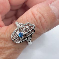 *  Sterling Silver Hamsa Tiny Blue Sapphire CZ Ring, Hand of God Ring, Religious Ring, Hamsa Promise Ring, Silver Ring, Statement Ring, Love Ring, Boho Ring, Eye Ring, 925 Stamped *  Hamsa is primarily used to protect its owner from the Ayin Ha'ra also known as The Evil Eye Protective talisman that brings good fortune, health and happiness *  Perfect gift idea for any occasion: birthday, anniversary, engagement, graduation, bridesmaid, Mother's Day, Valentine's Day, Christmas, promise. *  Your p Blue Open Ring Crystal Birthstone, Blue Birthstone Crystal Open Ring, Blue Crystal Open Ring For Promise, Adjustable Spiritual Sapphire Ring As Gift, Blue Open Crystal Ring For Promise, Blue Birthstone Crystal Ring, Adjustable Blue Birthstone Jewelry, Blue Birthstone Crystal Ring For Promise, Blue Birthstone Crystal Promise Ring