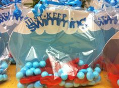 plastic bags filled with blue and red candies sitting on top of a wooden table