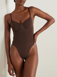 Designed to sculpt and define the figure, SKIMS' bodysuit is made from the label's stretchy compression fabric, which targets your core and waist. It has piqué stitches to outline the bust and a seamless thong at the back for a smooth finish under fitted clothing. Seamless Stretch One-piece Leotard, Fitted High-cut Leotard With Seamless Construction, Stretch Nylon Bodysuit With Built-in Bra, Seamless Fitted High-cut Swimwear, Sculpting Swimwear With Built-in Bra, Stretch High Cut Seamless Bodysuit, Fitted High Cut Seamless Swimwear, Fitted Seamless Elastane Leotard, Nylon Smoothing Fitted Bodysuit