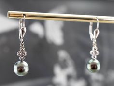 "The pearls on these elegant drop earrings are a deep, steely grey. Shimmering with subtle beauty, they are well matched and pair perfectly with the cool tones of the white gold. Polished bead accents add a touch of contemporary flair to these pretty earrings! Metal: 14K White Gold Gem: Pearl Gem Measurements: 8.4 mm, Round Earrings Length: 33 mm Earrings Width: 8 mm Marks: \"14K\" Stamped on the Findings SKU #: LALYJ8PV Each piece has been identified and graded by a Graduate Gemologist who has Elegant Gray Sterling Silver Earrings, Elegant Gray Jewelry With Matching Earrings, Elegant Gray Earrings As Gift, Elegant Gray Earrings For Gift, Silver Tahitian Pearl Earrings For Wedding, Elegant Gray Jewelry For Formal Occasions, Elegant Silver Tahitian Pearl Earrings, Luxury Silver Tahitian Pearl Earrings, White Gold Drop Earrings