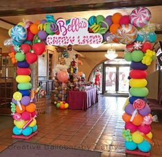 an entrance decorated with balloons and streamers for a candy land themed birthday party or baby shower