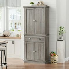 a tall cabinet in the corner of a kitchen next to a table and stools