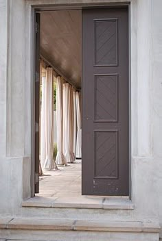 an open door leading into a room with curtains on either side and the floor below