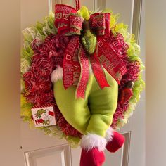 a christmas wreath hanging on the front door with santa's helper stocking around it