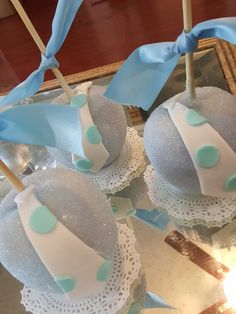 blue and white cake pops with bows on them sitting on doily in front of a mirror