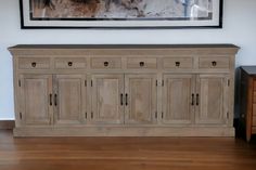 a large wooden cabinet sitting on top of a hard wood floor next to a painting