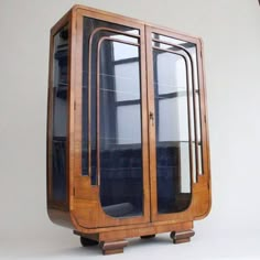 an old wooden case with glass doors on the front and sides, sitting against a white wall