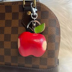 an apple keychain is attached to a louis vuitton bag