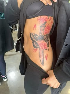 a woman with a butterfly tattoo on her stomach holding a knife in her right arm