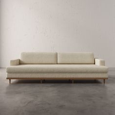 a white couch sitting on top of a cement floor next to a wall in an empty room