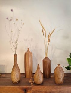 three wooden vases sitting on top of a table next to flowers and greenery