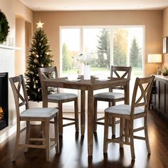 a dining room table with four chairs and a christmas tree in the corner next to it