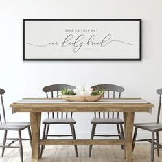 two framed pictures on the wall above a dining room table with chairs and a candle