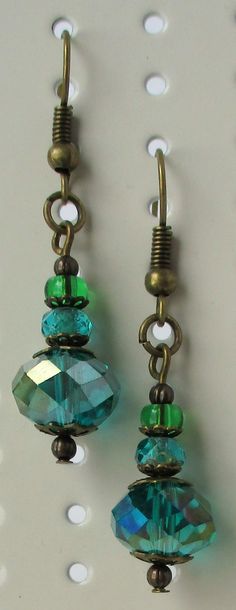 two pairs of blue and green glass beads hanging from brass earwires on a white background