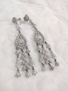 These earrings are to DIE for!! These stunning beautiful pieces are authentic 1920s art deco rhinestone. The silver tone pot metal is loaded with rhinestones and has a screw back style. These are SUPER long and GORGEOUS!! These are PERFECT for the Gatsby wedding or themed event. Please see all pictures on this pair for a better description and sizing. 13 Vintage Chandelier Earrings For Anniversary, Vintage Chandelier Dangle Earrings For Anniversary, Vintage Dangle Chandelier Earrings For Anniversary, Art Deco Silver Dangle Bridal Earrings, Silver Art Deco Dangle Bridal Earrings, Silver Art Deco Bridal Earrings With Dangle Shape, Art Deco Silver Drop Bridal Earrings, Silver Art Deco Drop Bridal Earrings, Silver Art Deco Bridal Drop Earrings