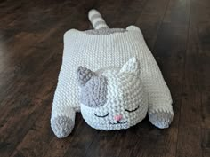 a knitted cat laying on the floor with its eyes closed and nose wide open