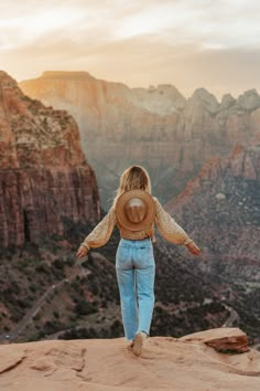 a woman standing on top of a mountain with her arms outstretched