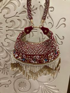 a red purse with tassels hanging from it's side on a wall