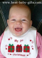 a smiling baby wearing a bib with presents on it's chest and saying, my 1st christmas