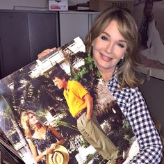 a woman holding up a magazine in an office