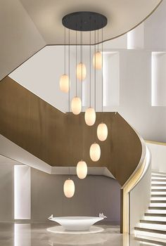 a bunch of lights hanging from the ceiling in a room with white walls and stairs