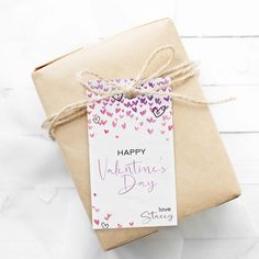 a gift wrapped in brown paper with a tag on it that says happy valentine's day