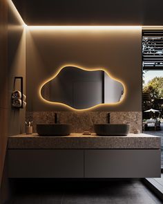 a bathroom with two sinks and a large mirror on the wall above it is lit up by lights