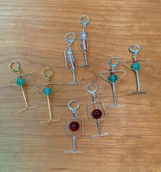 six different metal items on a wooden table with beads and charms hanging from it's sides