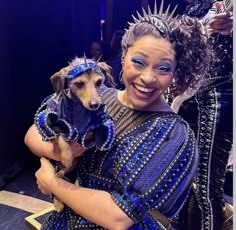 a woman holding a small dog in her arms and wearing blue clothes with spikes on it's head