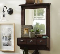 there is a mirror, potted plant and other items on the shelf in this room