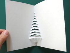 someone is holding an open book with a christmas tree cut out of the inside of it