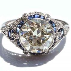 a fancy diamond ring with blue and white stones on it's sidestone, set in 18k white gold