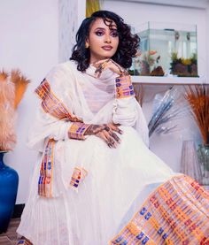 This radiant Habesha Kemis is a true masterpiece of Ethiopian fashion. The dress features a stunning Tilf design that is intricately woven into the fabric, creating a beautiful and unique pattern that catches the eye. The Tilf design is complemented by the Tilet bottom of the dress, which adds a touch of elegance and sophistication to the overall look. The Habesha Kemis is made from high-quality fabric that is soft to the touch and drapes beautifully on the body. The dress is designed to flatter White Bohemian Dress With Cutdana, Festive White Dresses With Woven Motifs, Festive White Dress With Woven Motifs, Handloom Long Sleeve Wedding Dress, White Maxi Sets For Traditional Ceremonies, Sheer Dupatta Dress For Navratri Ceremonies, Multicolor Handloom Dress With Traditional Drape, White Dabka Gown For Designer Wear, Designer White Gown With Dabka Detailing