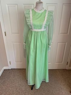 This nice vintage 1970's Mint green & white Swiss Dot and Lace Pinafore dress comes to you in a size small. The dress is a high waist style fully lined-has sheer sleeves and giant ruffle at bottom with lace trim-Has the Pinafore Front-In great vintage cond-Pls compare the measurements I give you to those in your closet-They are as follows- -14 3/4 to 15 inches shoulder to shoulder -25 1/2 inches shoulder to bottom of sleeve -waist is 14 inches across -hips N/A -49 inches underarm to bottom o Green Vintage Ruffled Dress For Spring, Green Retro Vintage Dress, Retro Green Long Sleeve Maxi Dress, Green Long Sleeve Retro Maxi Dress, Green Vintage Dress For Summer, Green Vintage Style Dress For Summer, Vintage Long Sleeve Green Dress, Green Ruffled Vintage Dress, Green Vintage Dress With Ruffles