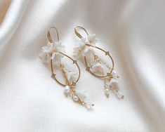 Our Irena teardrop Hoop Floral earrings for Bride are designed to be show stopping dangle hoops that will have everyone asking "where did you get those?!" Crafted with off white flower clusters & dangling freshwater pearls and white opal Austrian crystal beads, these earrings are perfect for casual or formal wear. - Handcrafted with genuine Austrian crystals- Created in my studio in PA- White opal crystals- Freshwater pearls- Polymer clay flowers- Yellow gold finish.- Earrings measure 3.25 inches x 1 inch- Handcrafted in the US.- Nickel free and hypoallergenic- PLEASE ALLOW APPROX 10 BUSINESS DAYS FOR COMPLETION BEFORE SHIPPING.This is an original design by © Treasures by Agnes Bridal Backdrops, Bridal Backdrop Necklace, Earrings For Bride, Gold Bridal Hair Comb, Backdrops Necklace, Crystal Bridal Earrings, Cubic Zirconia Bracelet, Flowers Yellow, Rose Gold Bridal