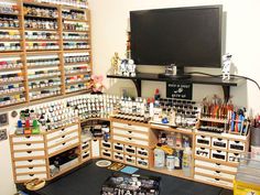 a room filled with lots of crafting supplies and bottles on the wall next to a flat screen tv