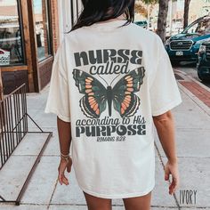 a woman walking down the street wearing a white shirt that says nurse called according to her purpose