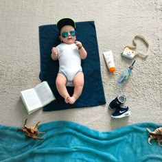 a baby is laying on a towel with an open book and other items around him