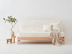 a white couch sitting next to a small table with a potted plant on it