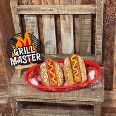 three hot dogs in buns sitting on a red tray next to a grill master sign