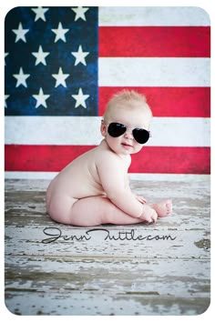 a baby wearing sunglasses sitting in front of an american flag