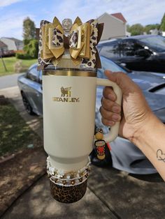 a person holding up a coffee mug with bows on it's top and leopard print wrap around the cup