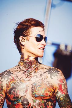 a man with tattoos on his chest wearing sunglasses