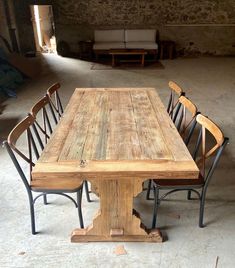 a wooden table with six chairs around it in an old warehouse like setting that is being used as a living room