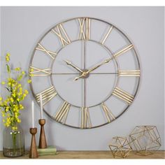 a large metal clock sitting on top of a table next to a vase with yellow flowers