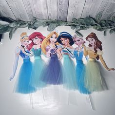 there are five princesses hanging on the wall in front of some leaves and branches