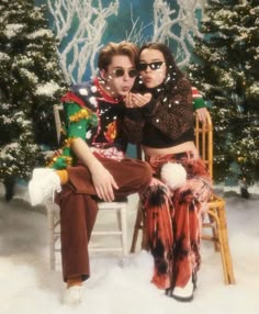 two women sitting on a chair in front of a christmas tree and snow covered ground