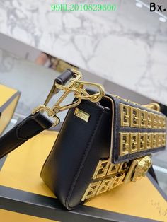 a black and gold purse sitting on top of a yellow table next to a box