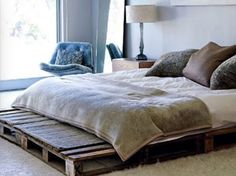 a bed made out of wooden pallets in a room with a large painting on the wall